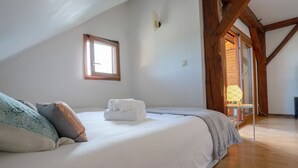 A bedroom with a large bed, a window, wooden beams, and a view of the outdoors. - Ecrin Vue Lac (Sévrier)