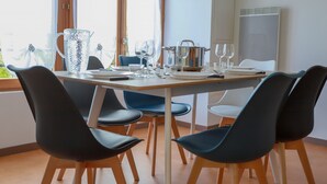 A dining area with a table set for four, including a pitcher, wine glasses, and a pot. - Ecrin Vue Lac (Sévrier)