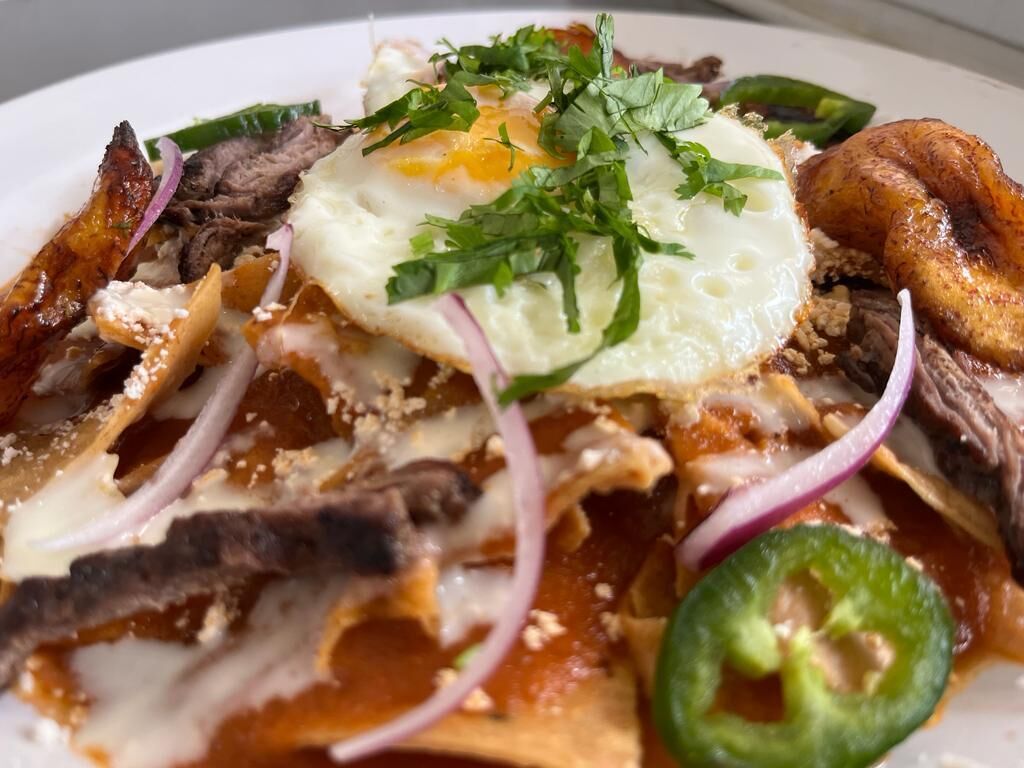Un plato de comida con un huevo frito, carne y verduras.