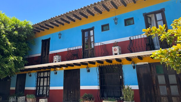 Un edificio colorido con fachada azul y amarilla, una puerta de madera y varias ventanas.