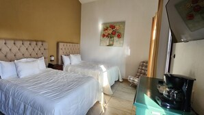 Una habitación de hotel con dos camas, una cafetera y un cuadro en la pared.