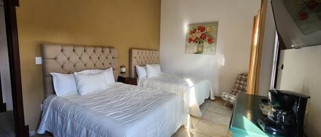 Una habitación de hotel con dos camas, una cafetera y un cuadro en la pared.