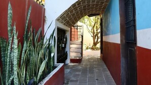 Un corredor exterior techado con techo de ladrillo, una escalera a la izquierda y una puerta a la derecha.