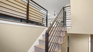 A staircase with wooden steps and metal railings, leading to an upper level with a beige wall and a window. - Bright, Spacious 4BD Suburban Nest w/Garage & Yard, hosted by DenverStays (Arvada)