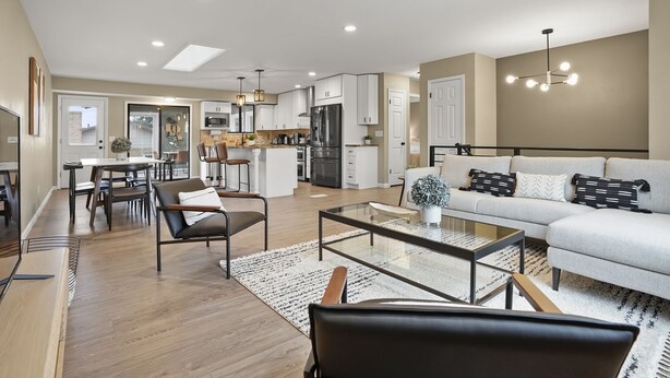 A modern living room with a sofa, coffee table, and chairs, a dining area with a table and chairs, and a kitchen with appliances and cabinets. - Bright, Spacious 4BD Suburban Nest w/Garage & Yard, hosted by DenverStays (Arvada)