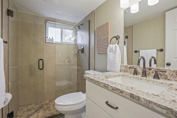A modern bathroom with a glass-enclosed shower, a white toilet, a marble sink with three faucets, and a large mirror. - Bright, Spacious 4BD Suburban Nest w/Garage & Yard, hosted by DenverStays (Arvada)