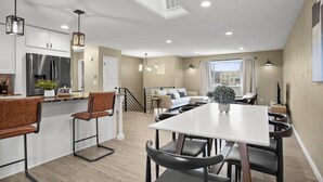 A modern kitchen with a central island, white cabinetry, and stainless steel appliances. - Bright, Spacious 4BD Suburban Nest w/Garage & Yard, hosted by DenverStays (Arvada)