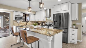 A modern kitchen with white cabinetry, stainless steel appliances, a granite countertop, and pendant lighting. - Bright, Spacious 4BD Suburban Nest w/Garage & Yard, hosted by DenverStays (Arvada)