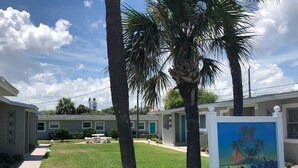 Un quartier résidentiel avec un panneau indiquant « SAND REEF » et une pelouse agrémentée de palmiers.