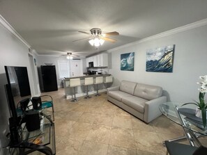 Relax in this stylish living space with a sofa, bar counter, and television.