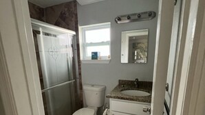 Une petite salle de bain comprenant des toilettes, un lavabo et une petite fenêtre.