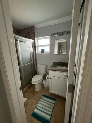 Bathroom features a modern design with a window offering a view of the outside, a sink, toilet, and refrigerator.