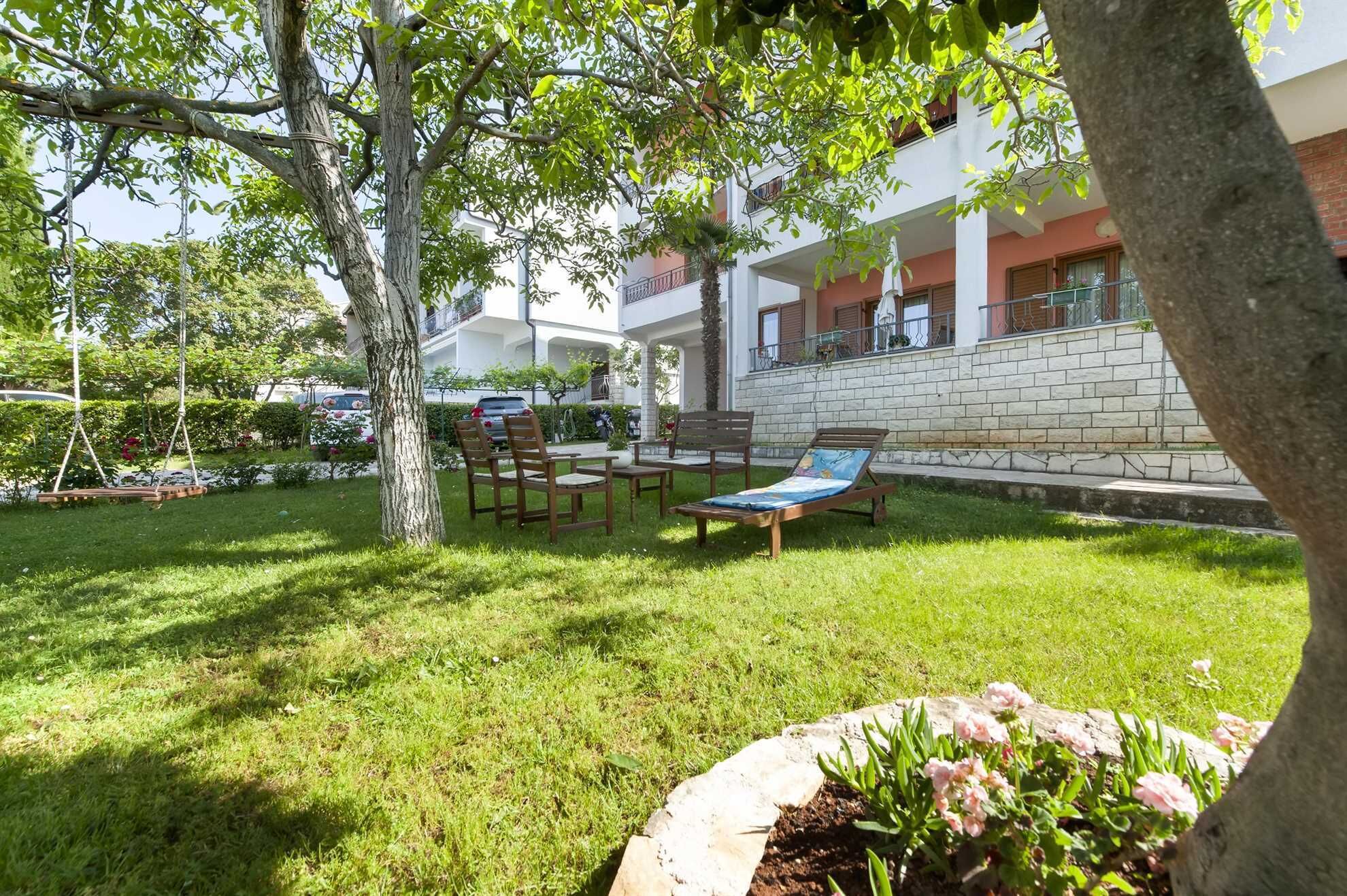 Une cour avec une balançoire, des fauteuils de jardin et un mur en briques.