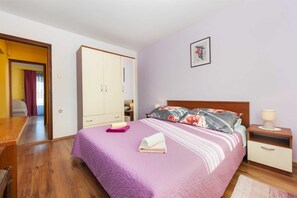 Ein Schlafzimmer mit Bett, Kleiderschrank, Nachttisch und einem gerahmten Bild an der Wand.