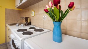A kitchen with a white stove, a coffee maker, and a blue vase with tulips.
