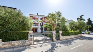 A gated residential area with a multi-story building, stone pillars, and a clear sky.