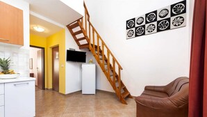 A modern kitchen with a wooden staircase, a white refrigerator, and a brown leather sofa. - ADRIA One-Bedroom Apartment with Balcony 2 (Rovinj)