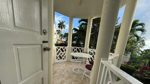 A covered outdoor area with a white door, a white table with two chairs, and a tiled floor. - Relax with us Casa de Columbus!
5- mins from the beach and other fun activities! (Ocho Rios)