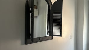 A wall-mounted mirror with a black frame and a door with horizontal slats. - The Lodge Oldham (Oldham)