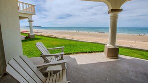 A covered patio with a view of a beach, a white chair, and a column. - Villa 20, Beachfront Las Palmas Resort (Puerto Penasco)