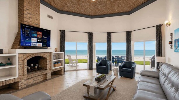 A living room with a fireplace, a flat-screen TV, and a view of the beach. - Villa 20, Beachfront Las Palmas Resort (Puerto Penasco)