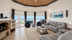 A living room with a fireplace, a grey sofa, a coffee table, and a view of the beach. - Villa 20, Beachfront Las Palmas Resort (Puerto Penasco)