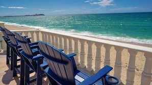 Une plage avec une rambarde et des chaises donnant sur l’océan.