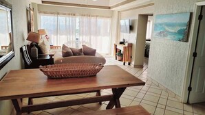 A spacious living area with a wooden table, a woven basket, a sofa, and a television. - Delphin 403A, Las Palmas Resort (Puerto Peñasco)