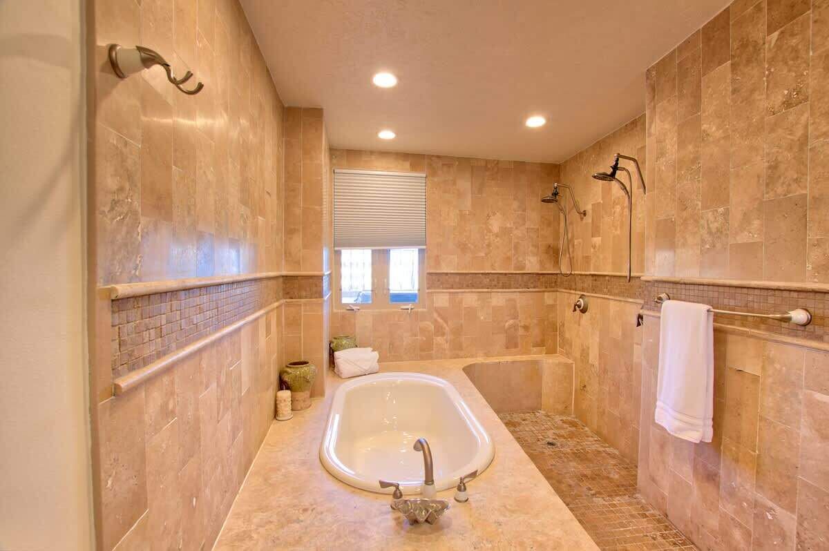 Un bagno con una vasca da bagno indipendente, una doccia e una finestra con persiane.