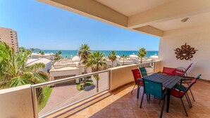 Balcón con mesa y sillas, vista a una playa y edificios.