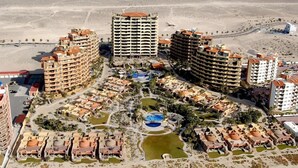 Un resort con varias edificaciones, una piscina central y vegetación circundante.