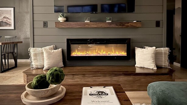 A modern living room with a fireplace, a coffee table with a book, and a sofa.