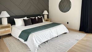 A modern bedroom with a large bed, two bedside tables, a ceiling fan, and a round wall decoration.