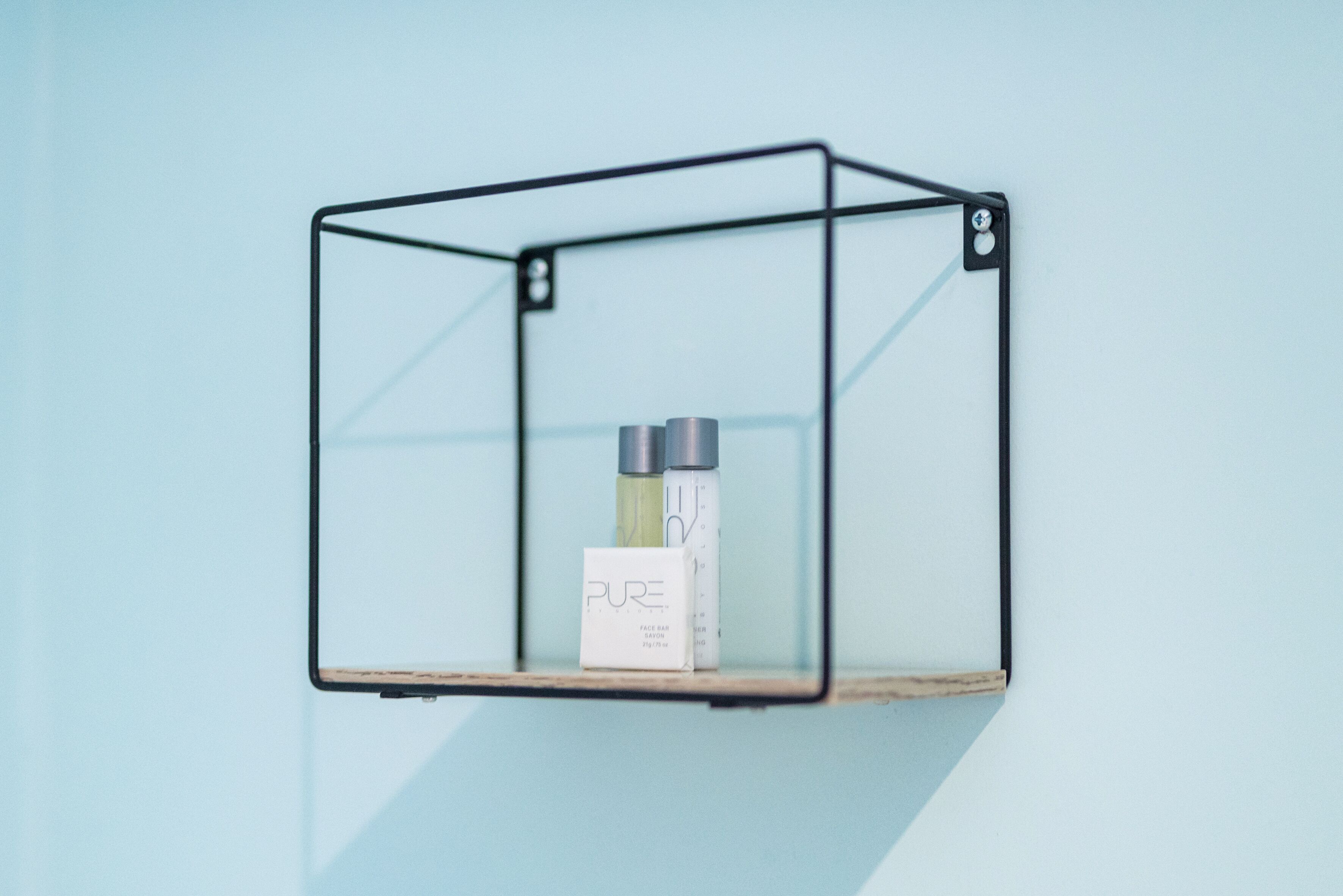 A minimalist shelf unit with a white box labeled "PURE" and two bottles.