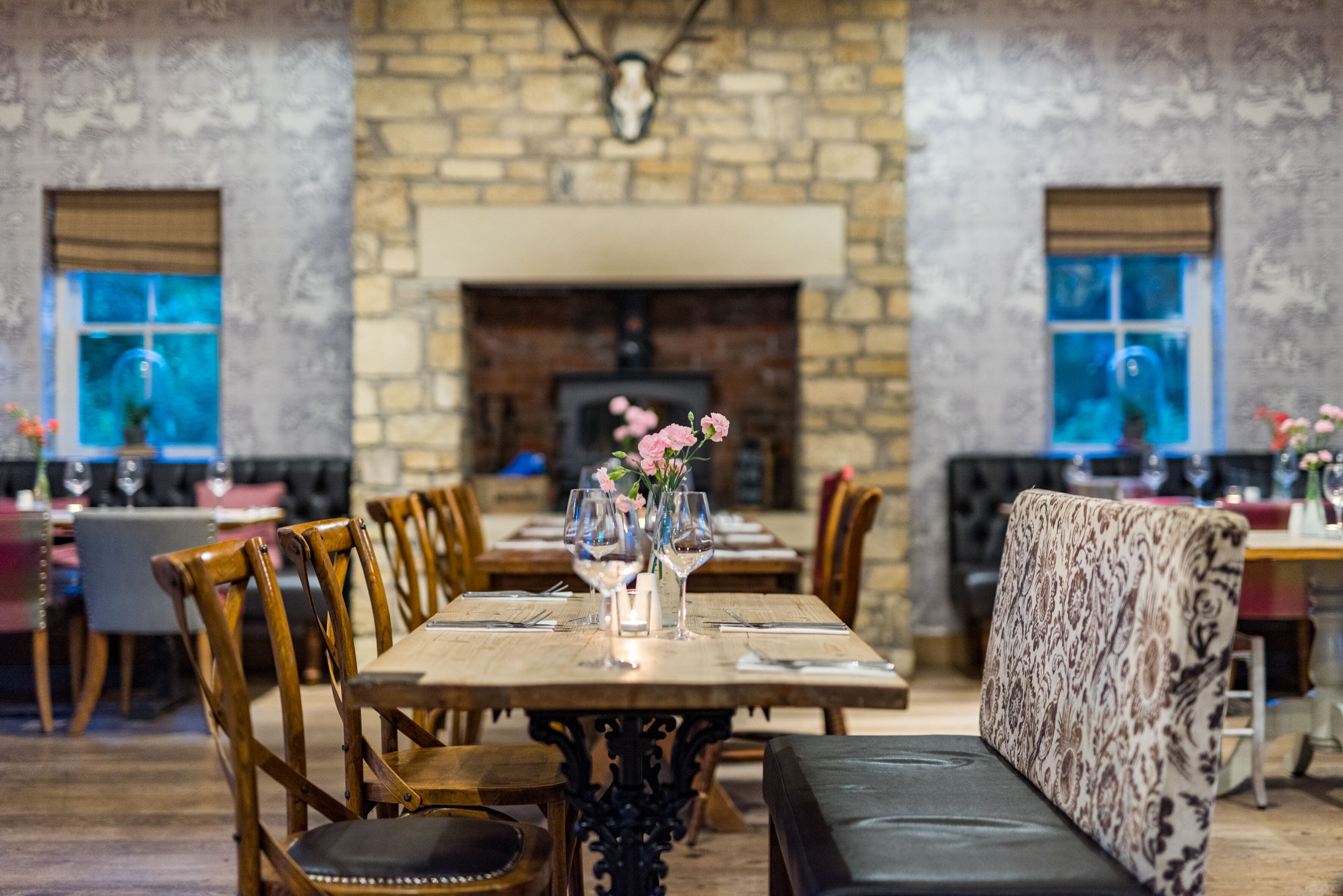 Un restaurant doté d’une cheminée en pierre, de tables et de chaises en bois.