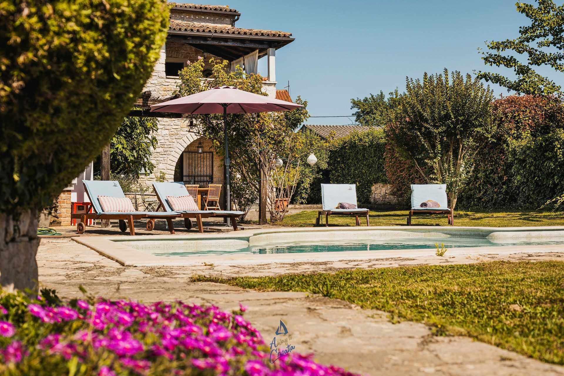 Un área junto a la piscina con sillones de descanso y una pérgola.
