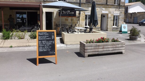 A restaurant with outdoor seating, a chalkboard menu, and a stone building facade. - Maison a Louer Situé au Bord de la Dordogne (Saint-André-de-Cubzac)