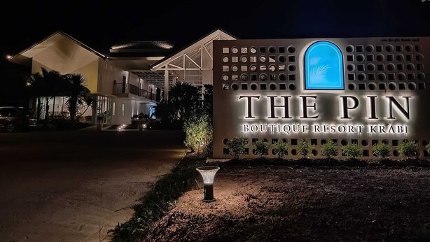 Schild des The Pin Boutique Resort Krabi bei Nacht.