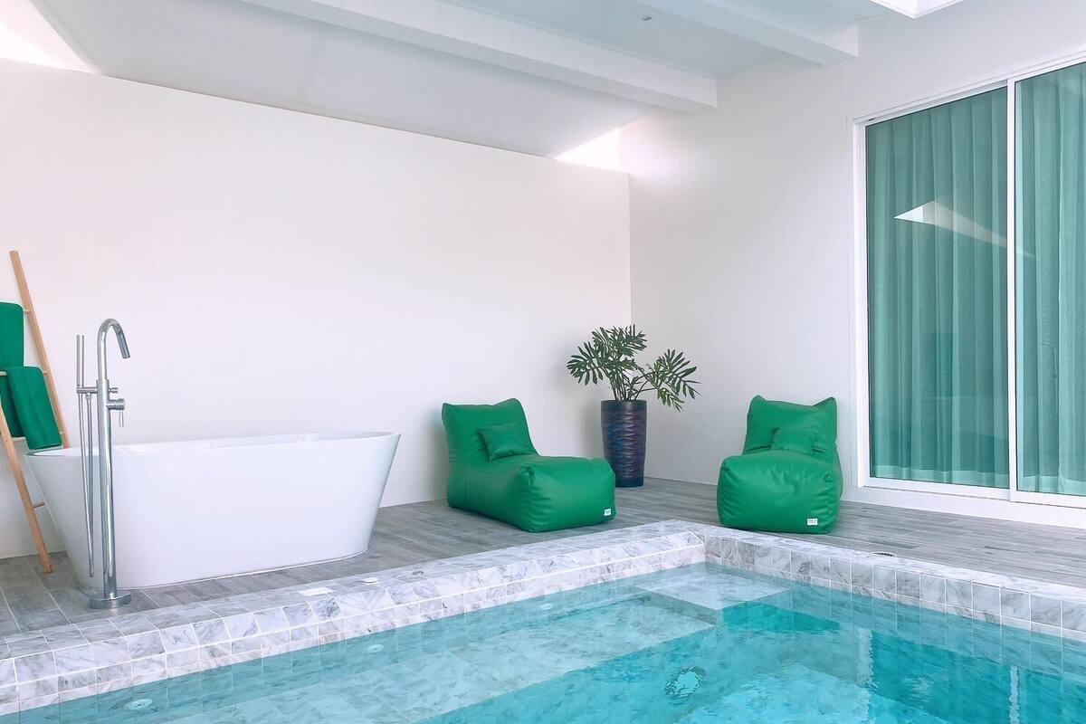 Une salle de bain moderne dotée d’une baignoire intégrée, d’une piscine entourée de parois en verre et de sièges verts.