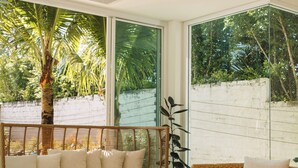 Ein modernes Wohnzimmer mit großem Fenster, Rattanmöbeln und einem gemusterten Boden.