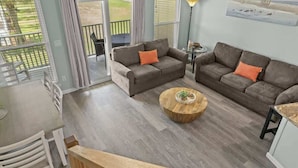 A spacious living area with two sofas, a round coffee table, and a view of the outdoors through large windows.
