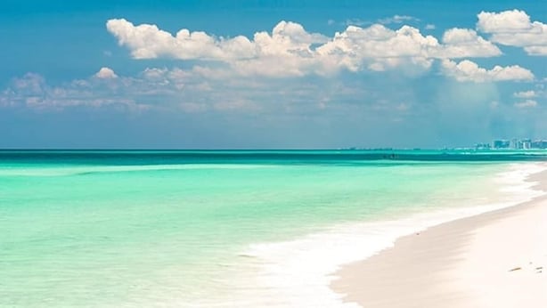 A beach with clear turquoise water and a sandy shore.