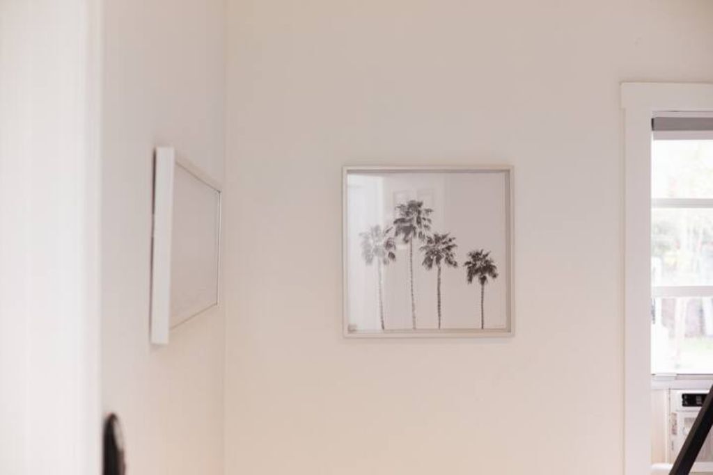 Un couloir orné d’un tableau encadré représentant des palmiers.