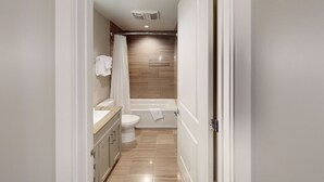 A modern bathroom with a toilet, vanity, and bathtub. - 60 Night Minimum Rental - FQ Apt. 2B/2B (New Orleans)