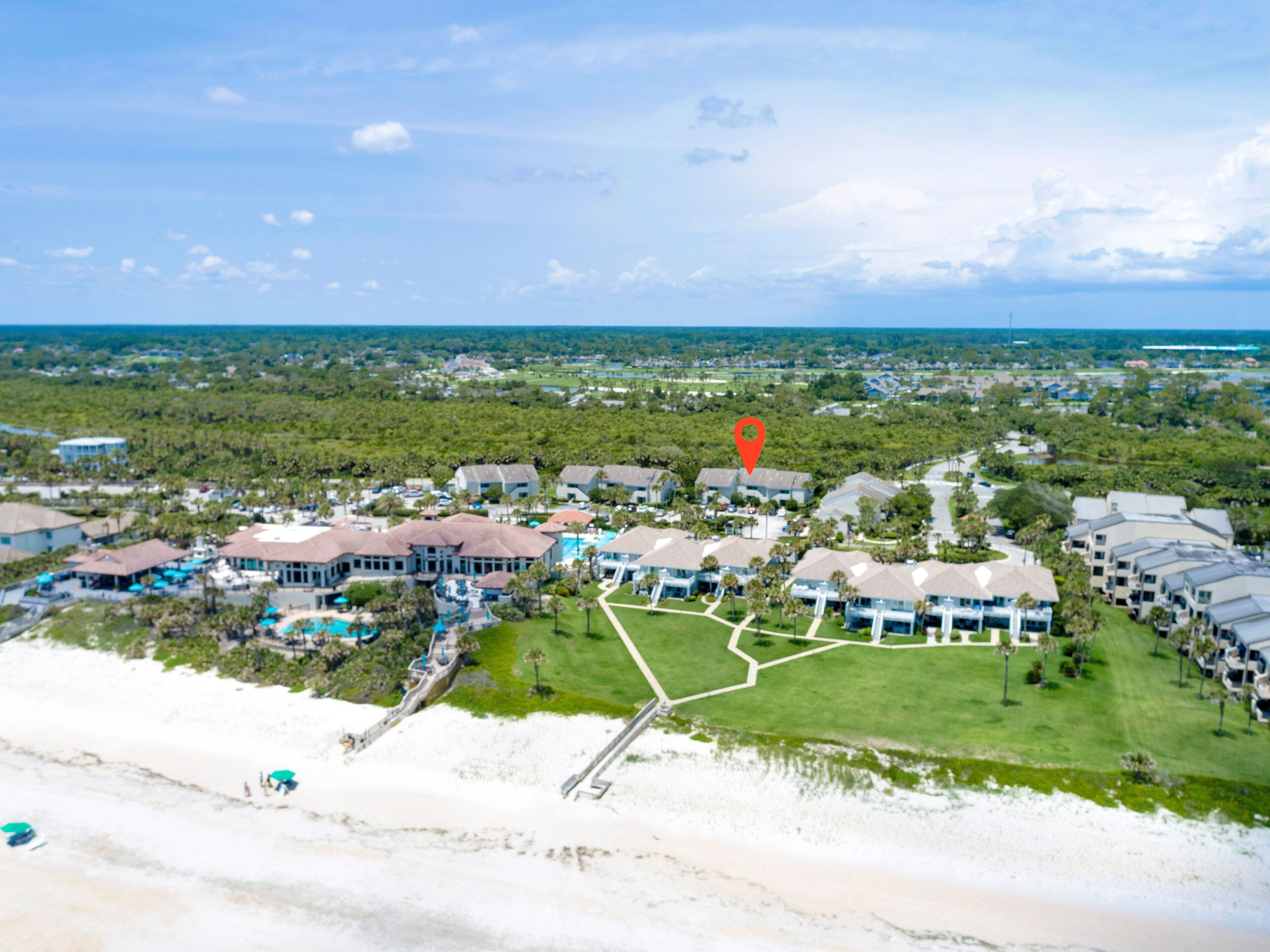 An aerial view of a resort with multiple buildings, a beach, and a golf course.