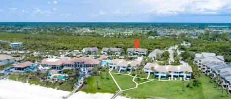 An aerial view of a resort with multiple buildings, a beach, and a golf course.