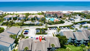 A resort with multiple buildings, a parking lot, and a beach in the background. - Just steps to the beach and located within the Sawgrass Beach Club!  (Ponte Vedra Beach)