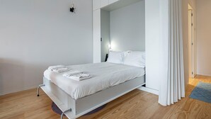 A modern, minimalist bedroom with a single bed, white bedding, and a wooden floor. - Nomad s Lux - Jardim Vista (Porto)