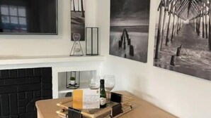 A modern living room with a fireplace, a flat-screen TV, and three framed artworks on the wall. - Modern 2BR Steps 2 Water Near Downtown! Fast Wifi (Lake Worth)