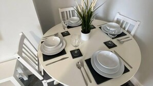 A round dining table with white plates, cutlery, and a centerpiece.